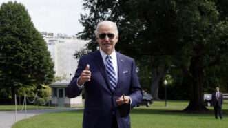 A photo of Joe Biden wearing sunglasses and giving a thumbs up in front of the White House