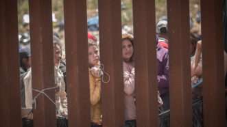 Women behind a border wall between Mexico and the US