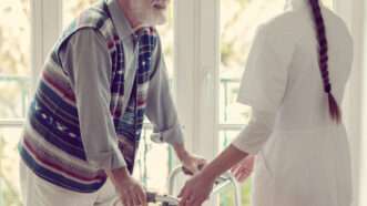 A female nurse helps a senior man in a nursing home