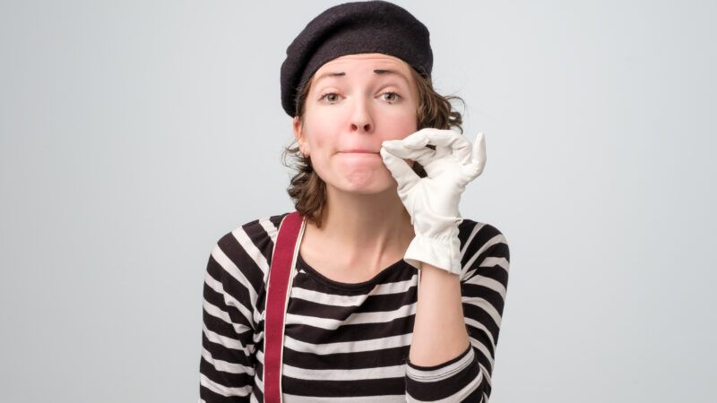 Female mime pretending to zip her mouth shut.