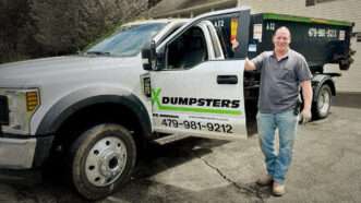 Steven Hedrick stands by his truck, labeled X Dumpsters, that he uses to transport Dumpsters.