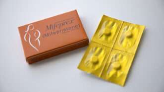 Mifepristone and misoprostol pills laid out against a white background.