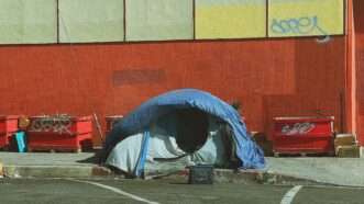 a homeless person's tent set up in a parking lot