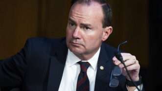 Sen. Mike Lee (R–Utah) at a Senate Judiciary committee meeting. He is holding his glasses in one hand and looking off to the side.