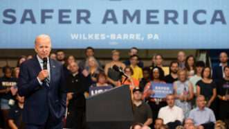 President Joe Biden addresses a crowd in Wilkes-Barre, Pennsylvania, beneath a giant banner reading "SAFER AMERICA"