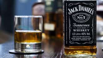 Bottle of Jack Daniel's next to a half full whiskey glass