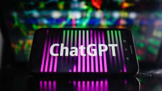 ChatGPT logo on phone in front of multi-colored high-tech background