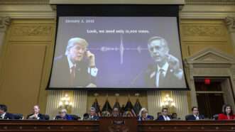 A projector screen at a congressional hearing showing Donald Trump