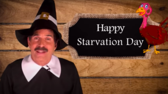 John Stossel dressed in a Pilgrim costume stands next to a sign that says "Happy Starvation Day"